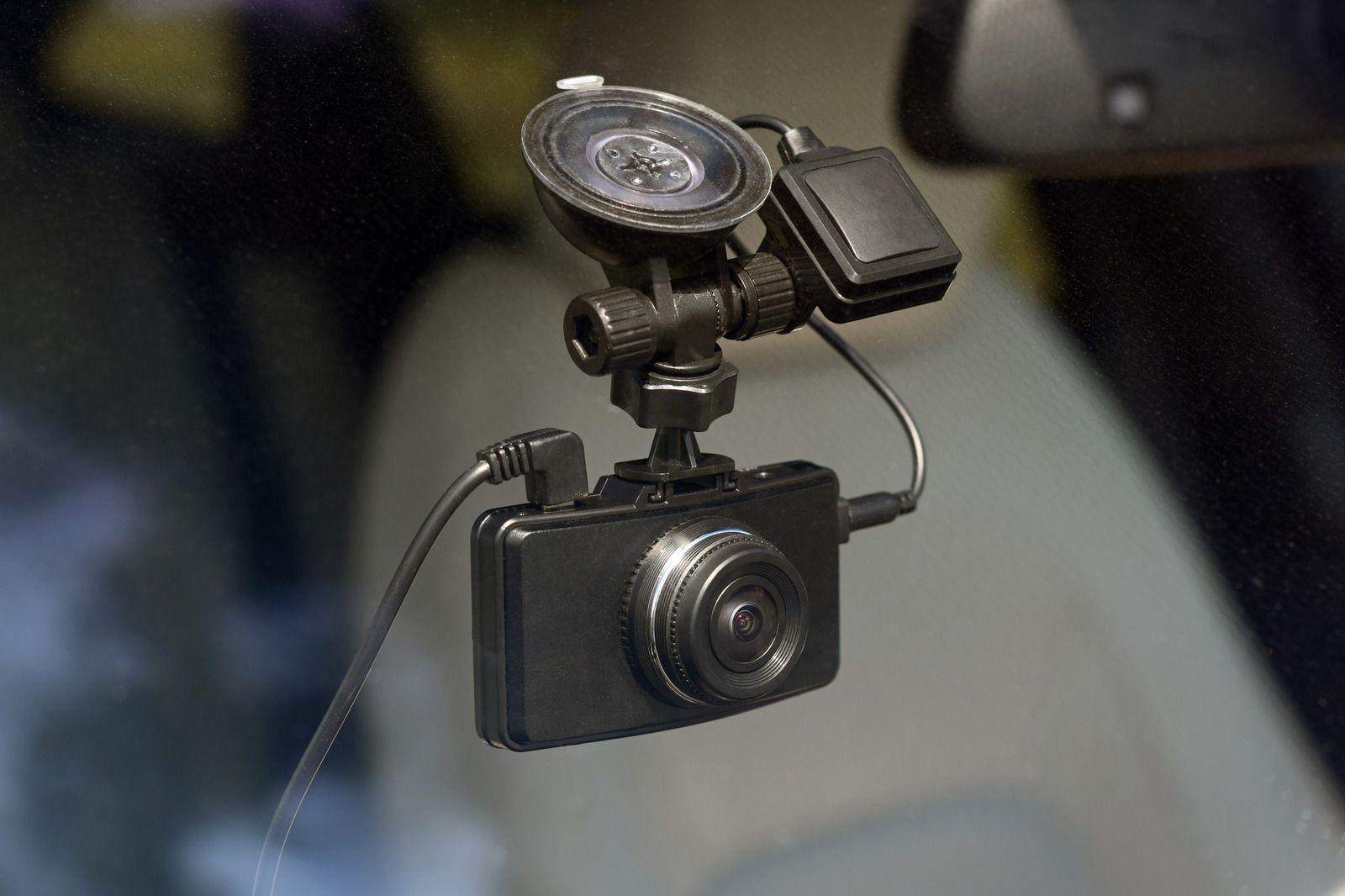 Dashboard camera with a small mounted light and microphone against a blurred car interior