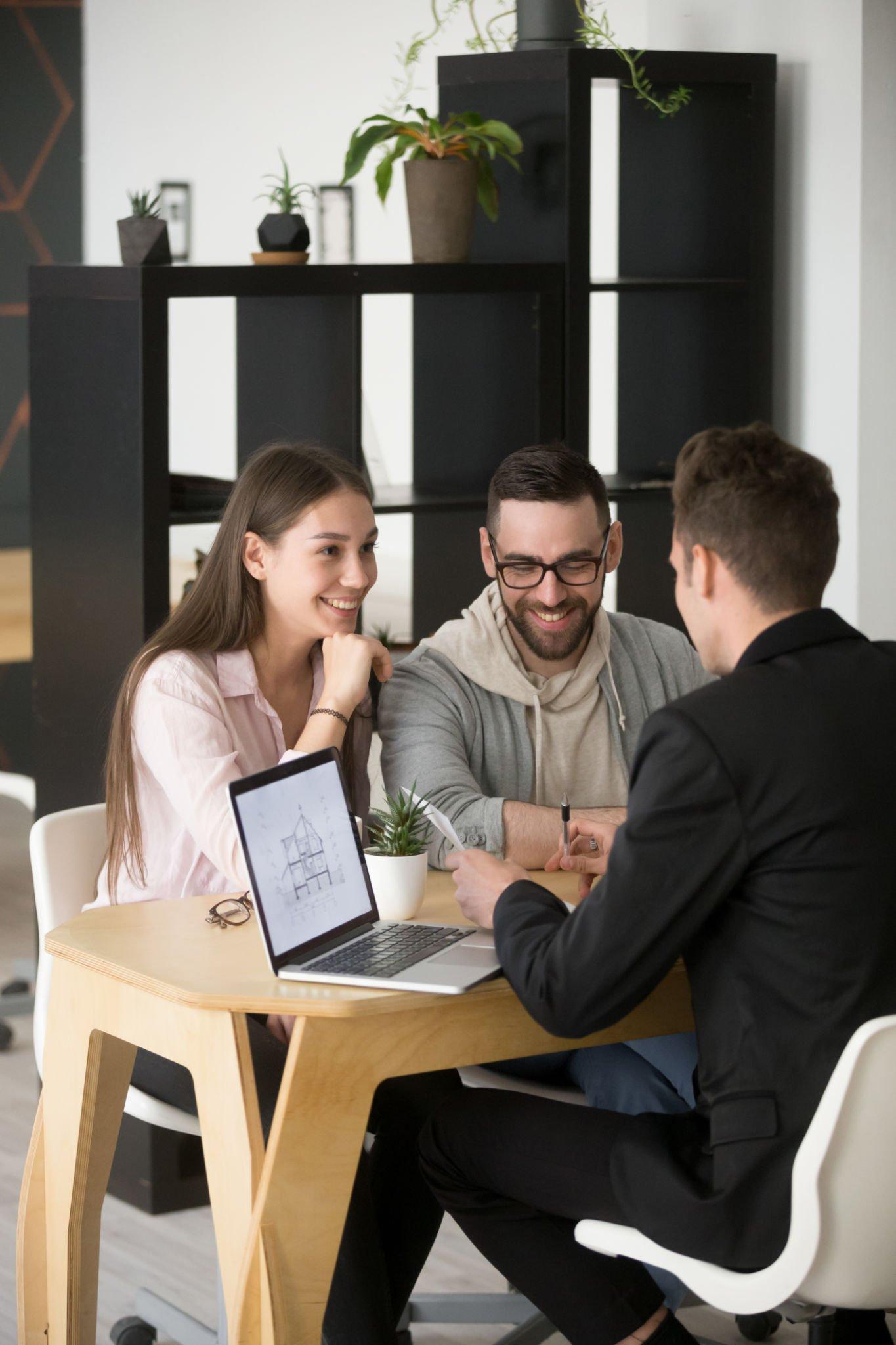 A man and a woman are sitting at a table with a laptop.