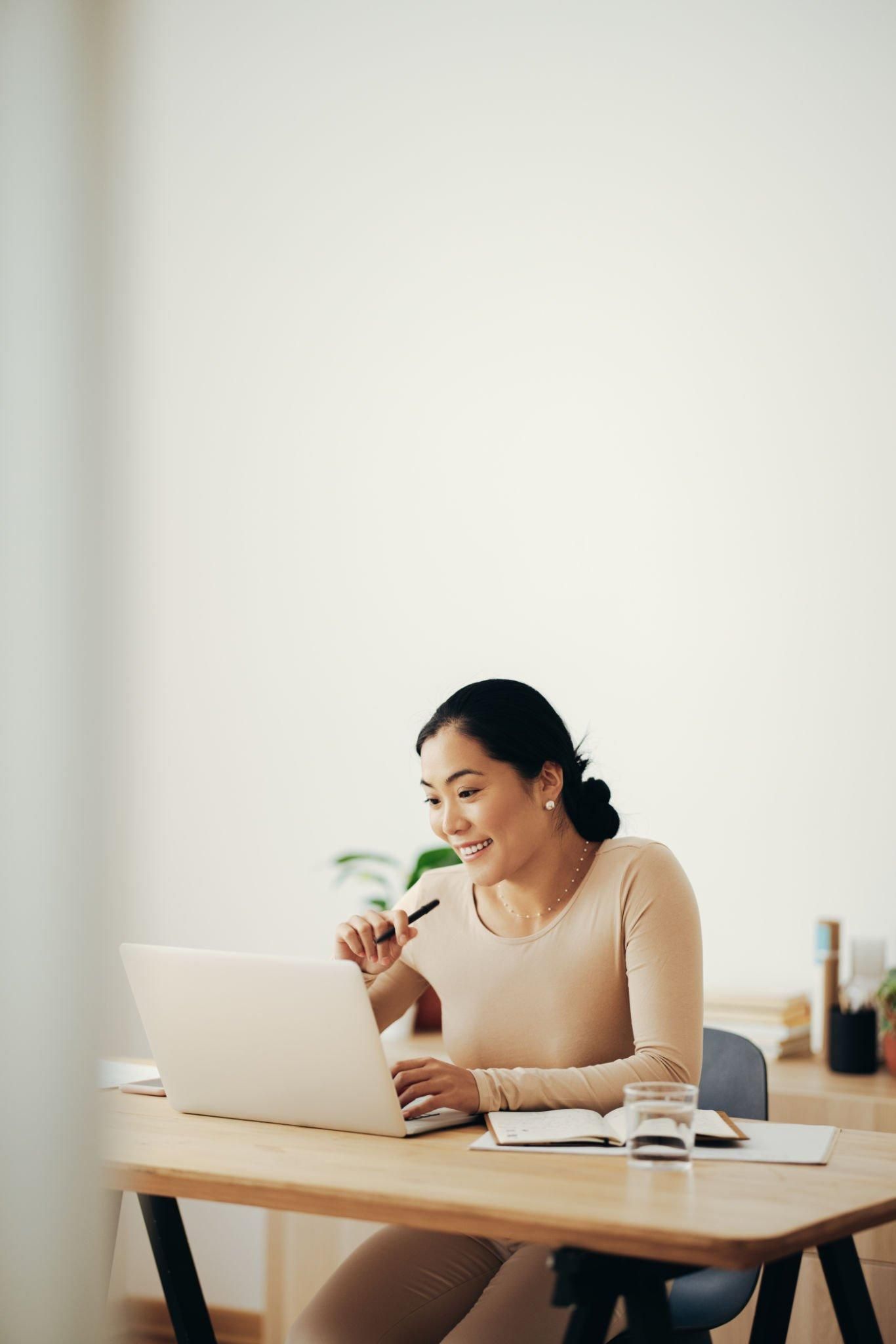 A woman is sitting at a desk using a laptop computer.