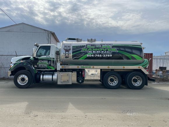 a green and white tanker truck is parked on the side of the road . | Mechanicsville, VA | C & W Hanover Septic Septic service truck with green and white graphics parked on a street.