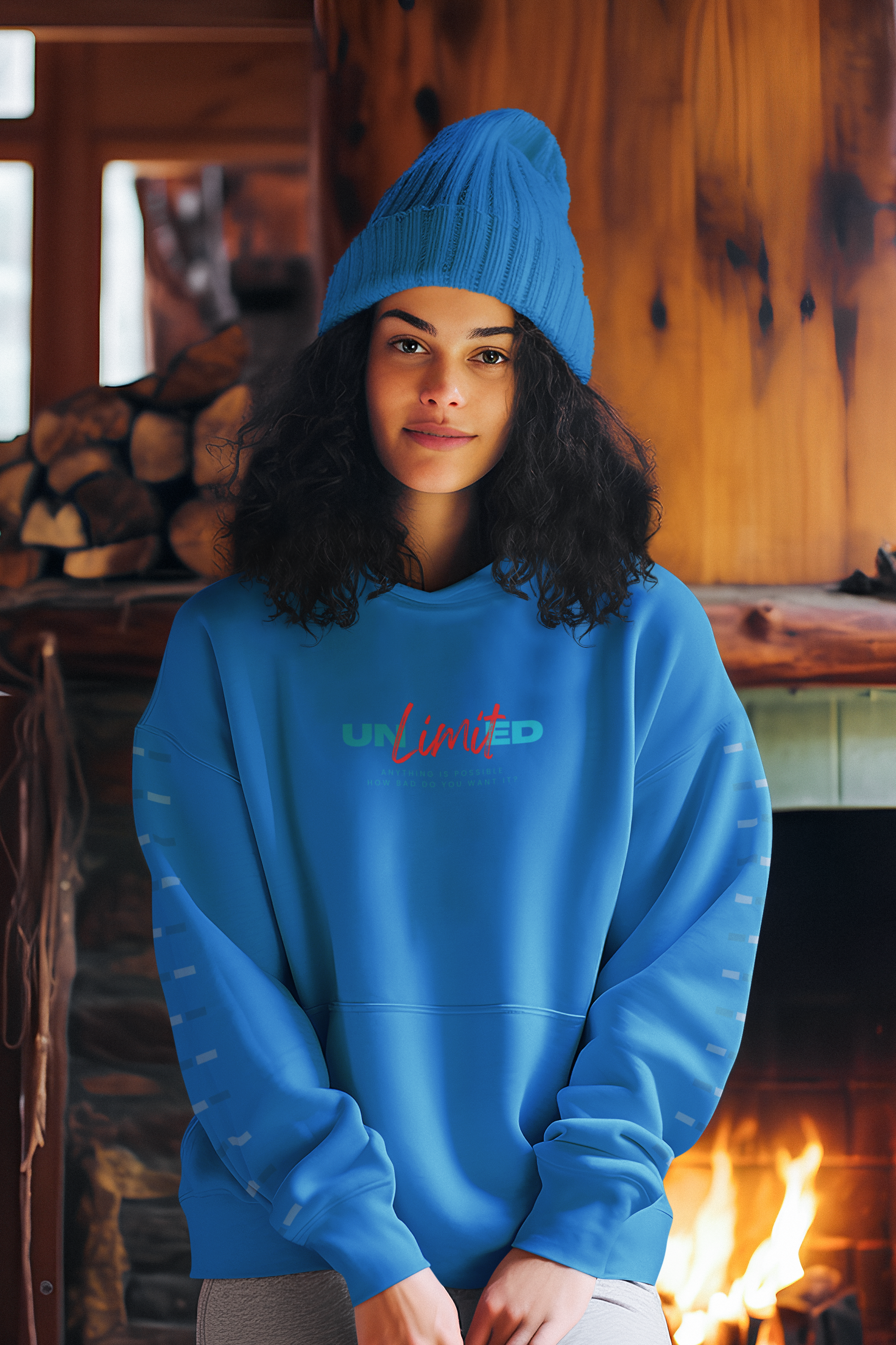 A woman wearing a blue sweatshirt and a blue hat is standing in front of a fireplace.