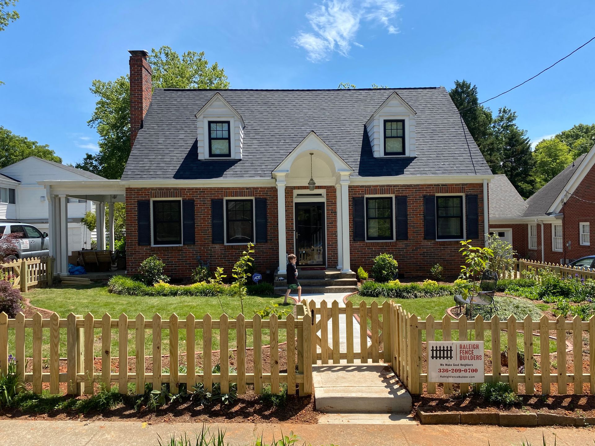 A brick house with a wooden picket fence in front of it