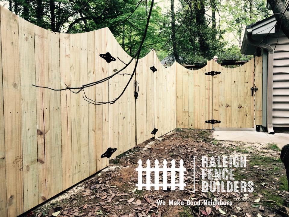 A wooden fence is being built in the backyard of a house.