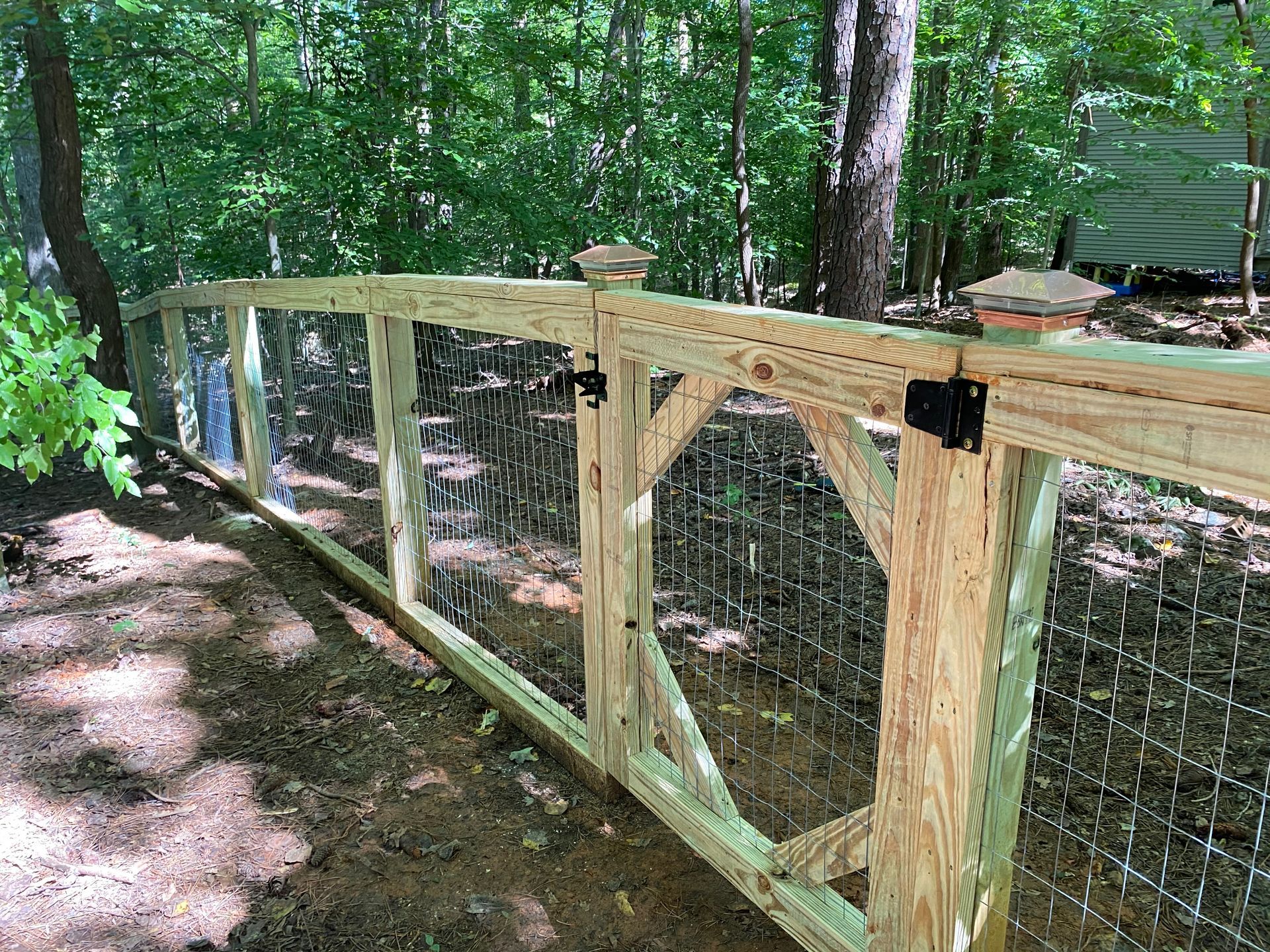 A wooden fence with a gate in the middle of a forest.
