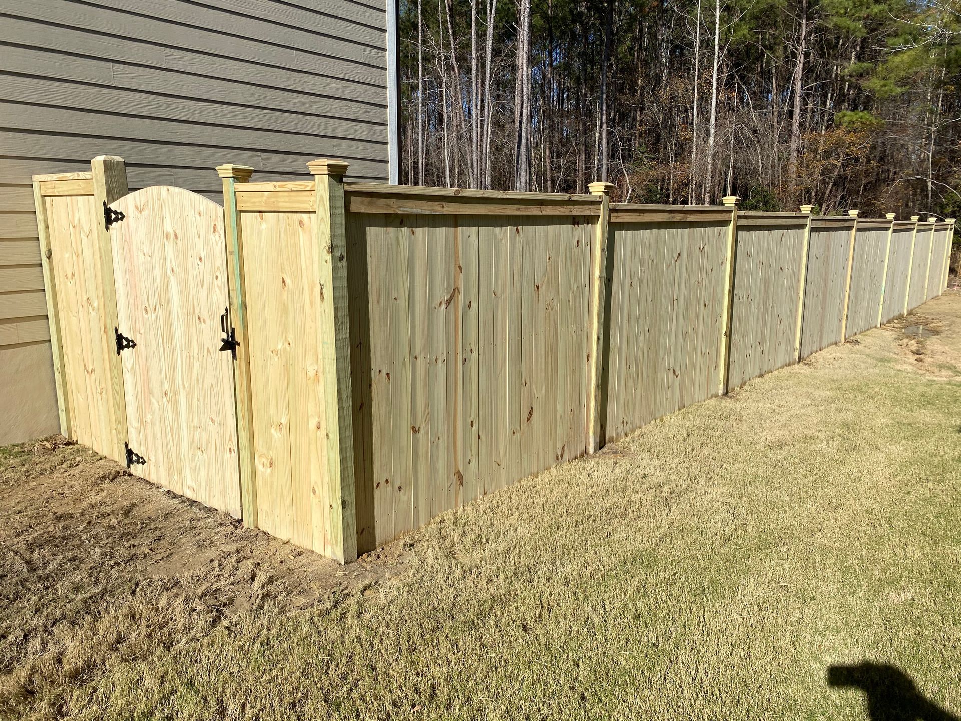 A wooden fence with a gate in the backyard of a house.