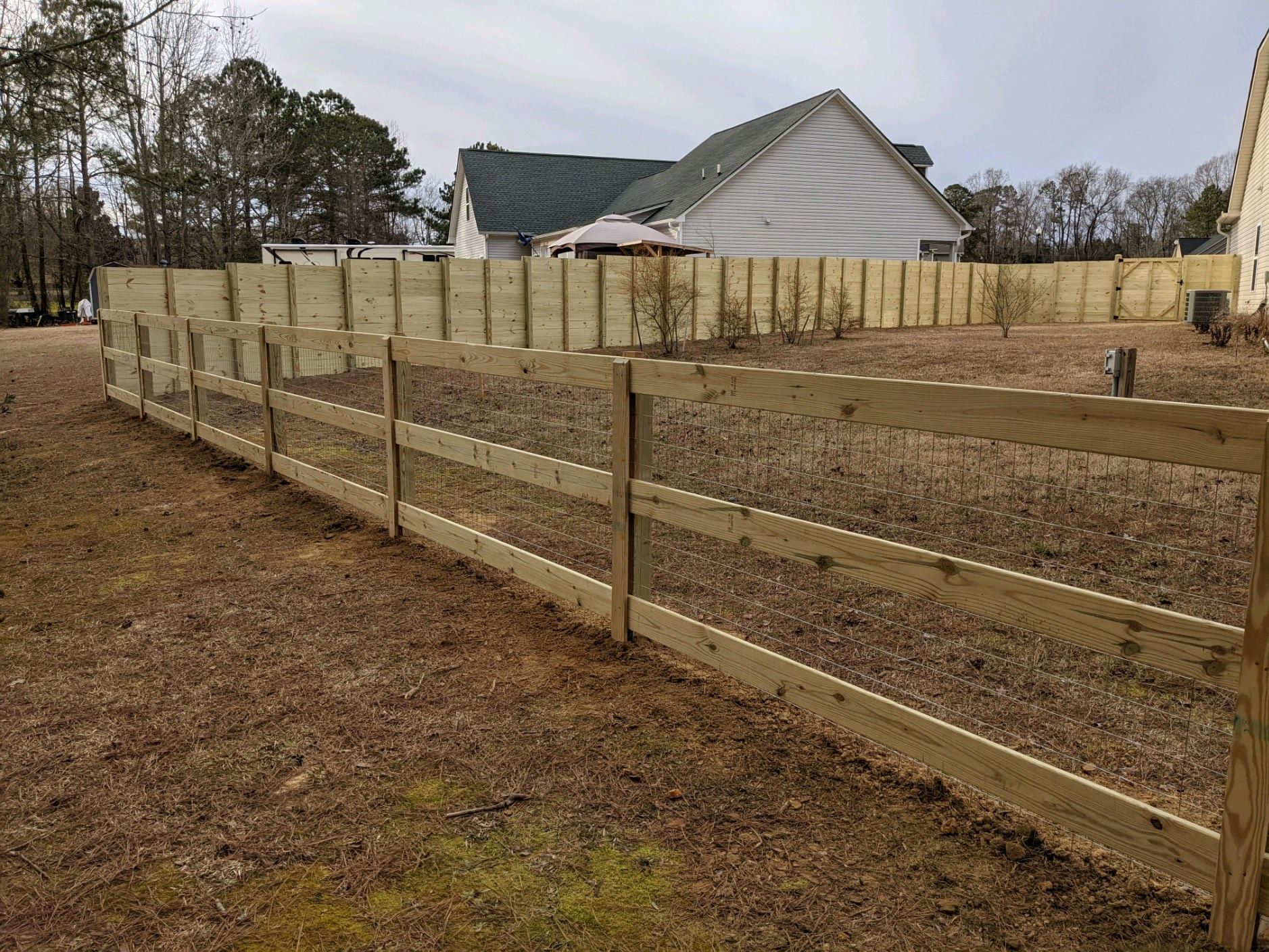 A wooden fence is in the backyard of a house.