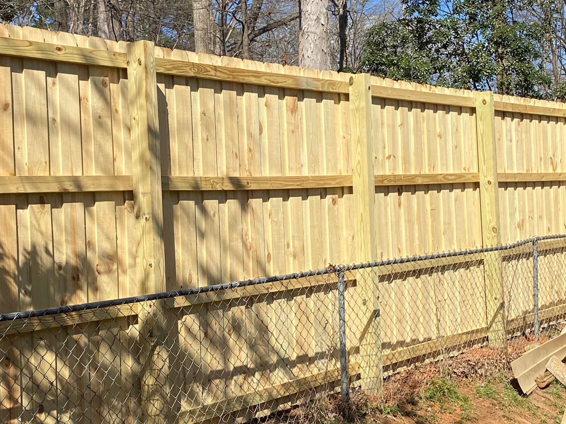 A wooden fence with a chain link fence behind it.
