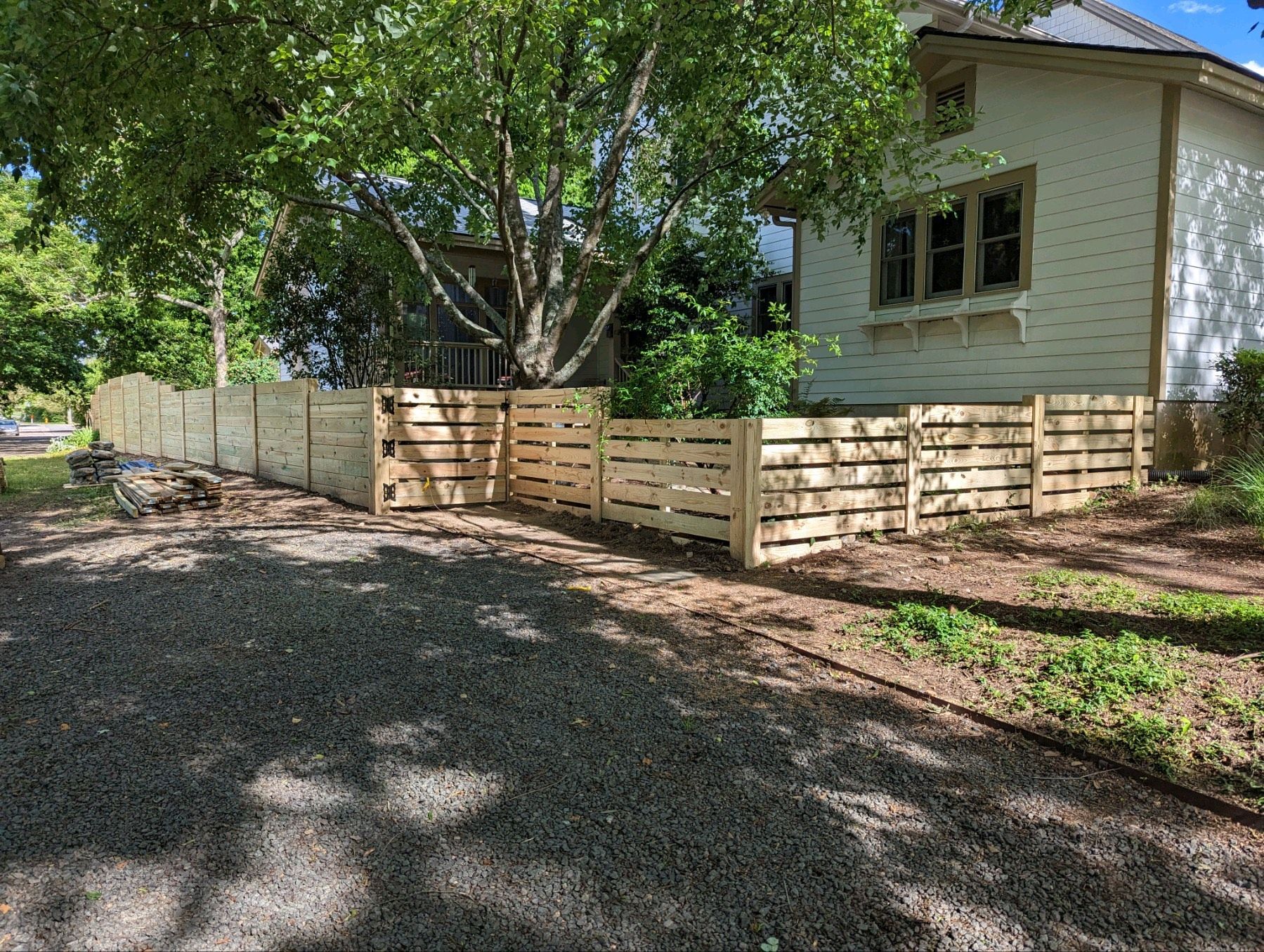 A wooden fence is in front of a white house.