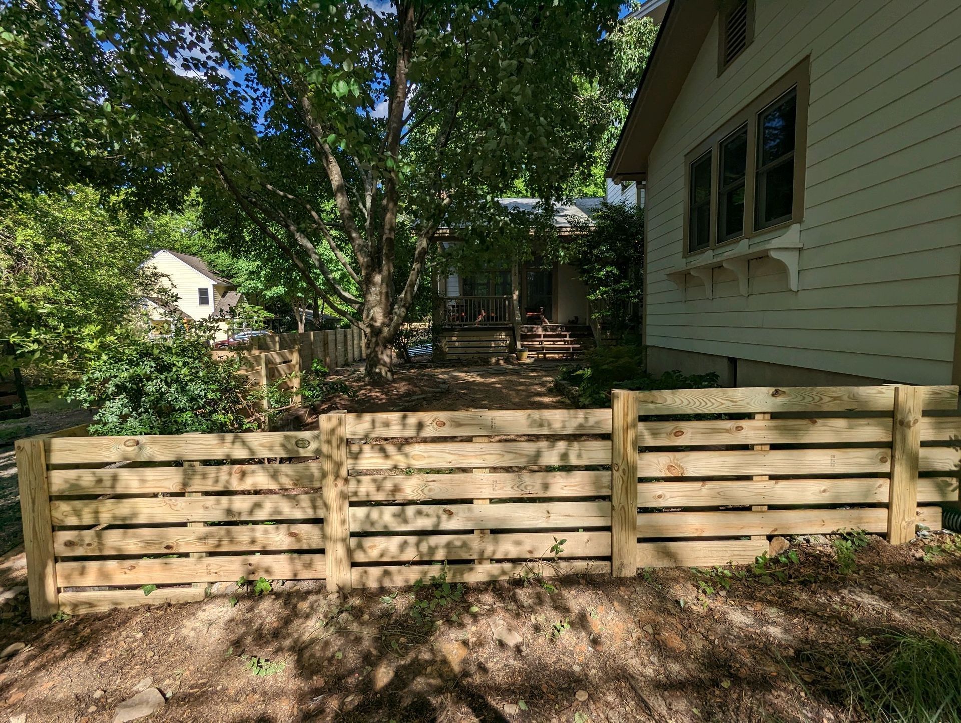 A wooden fence is in front of a house.