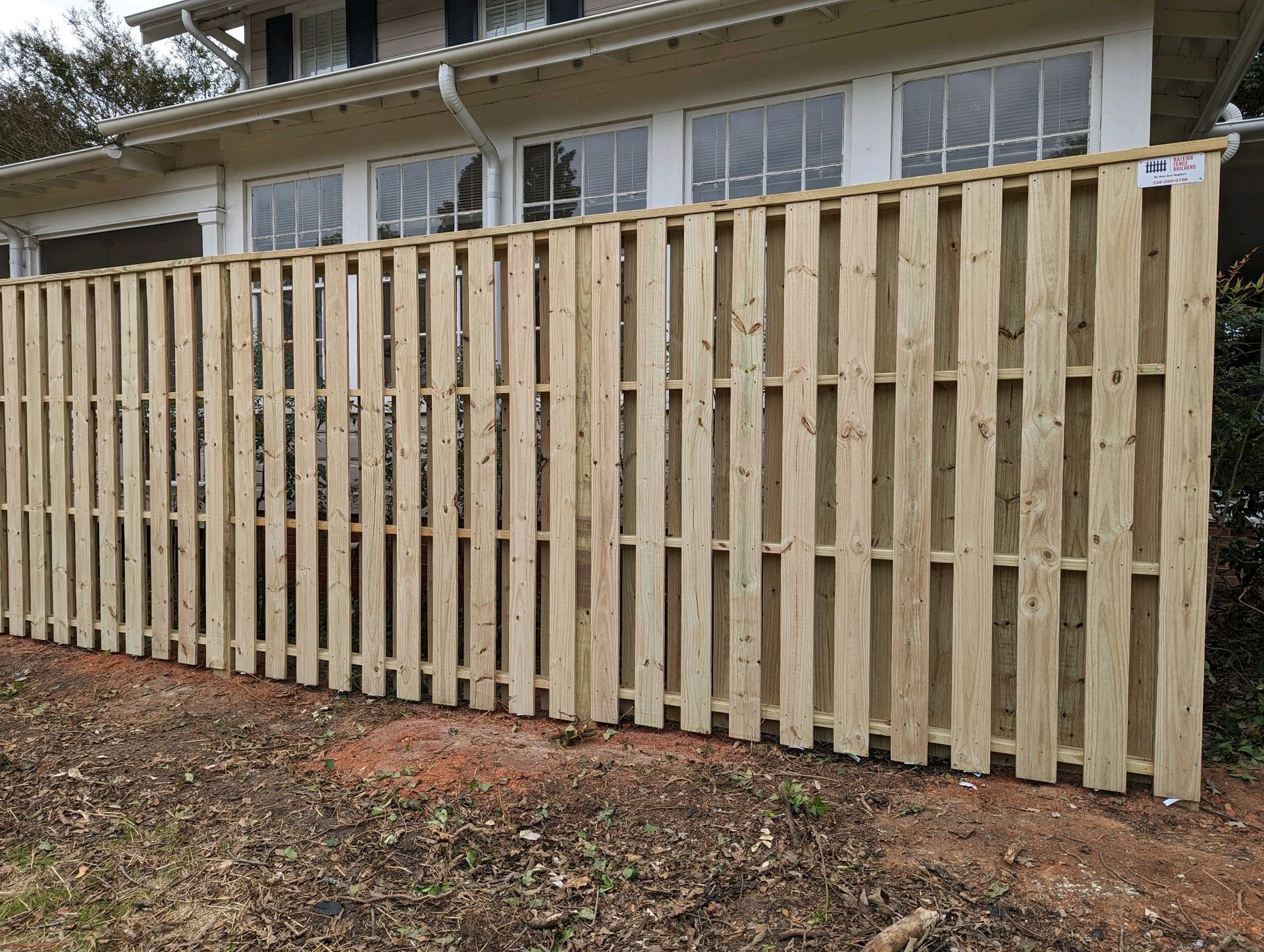 A wooden fence is sitting in front of a house.