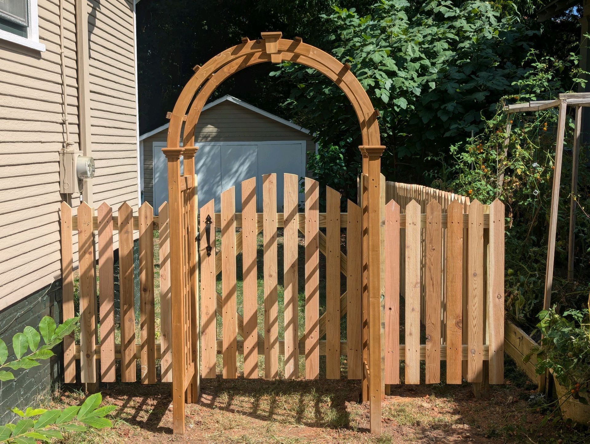 A wooden fence with a wooden arch in the backyard