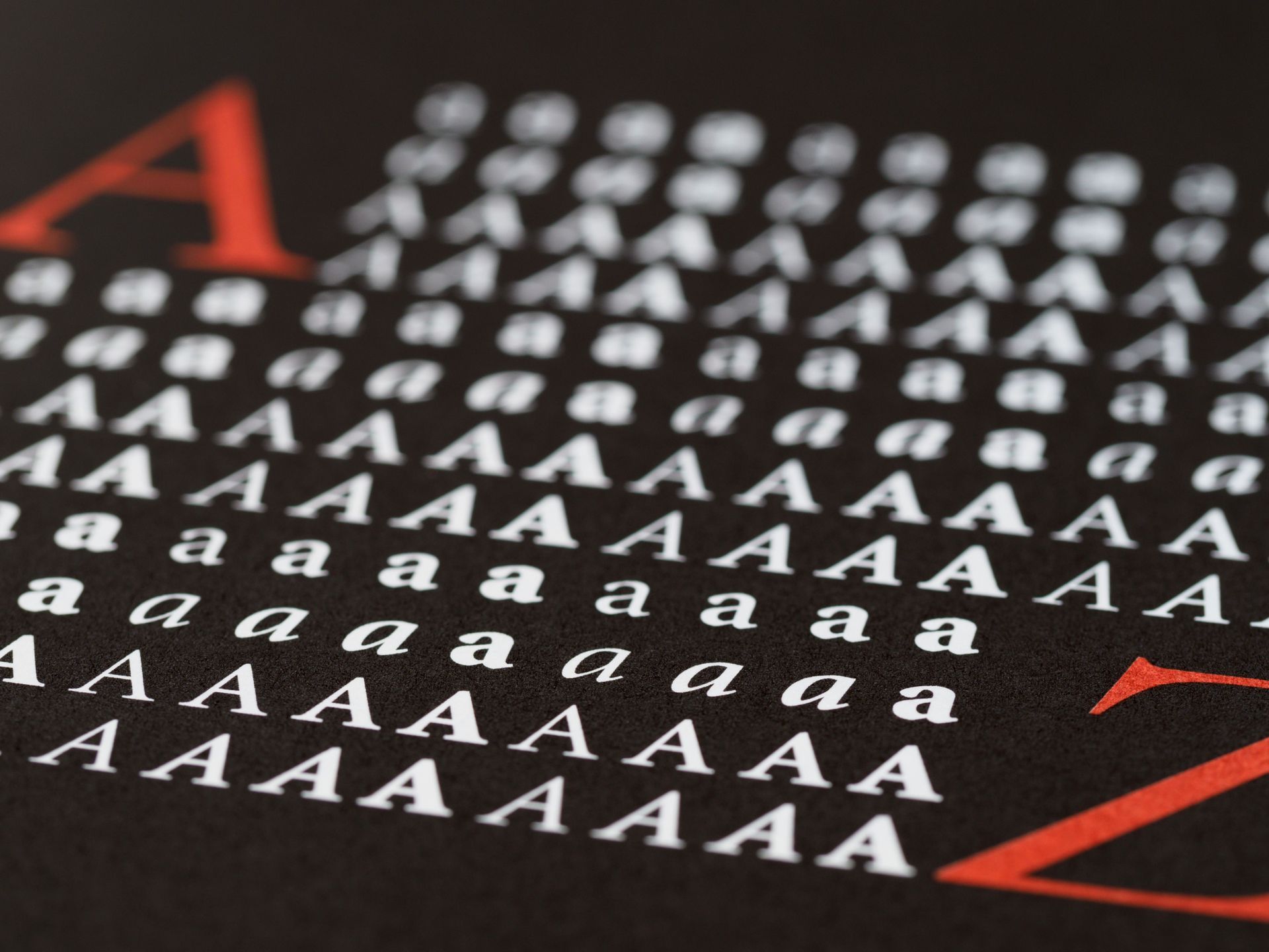 Primo piano di lettere e simboli stampati in bianco, rosso e nero su sfondo scuro.