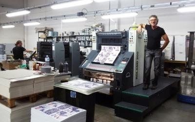 Macchina da stampa con un uomo in piedi accanto a una grande stampante industriale in un'officina