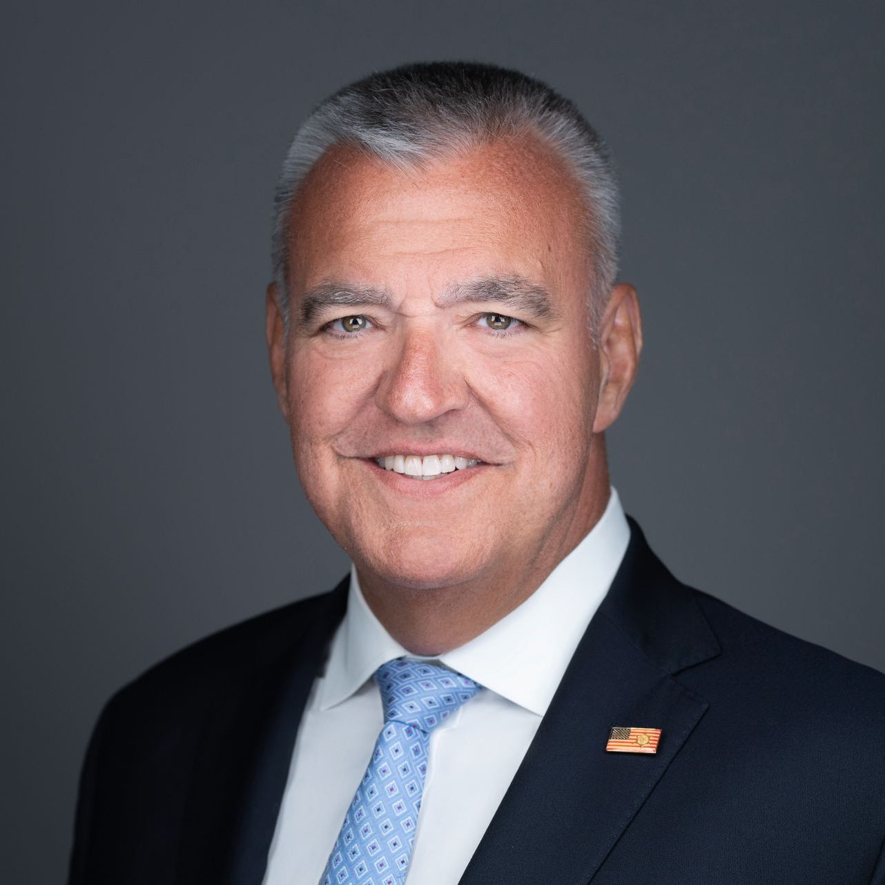 A man in a suit and tie is smiling for the camera.