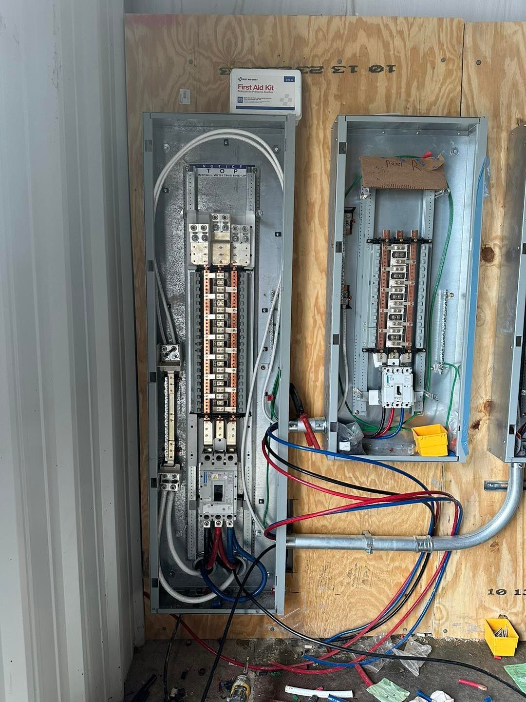 Electrical panels mounted on plywood, with wires and conduits visible.