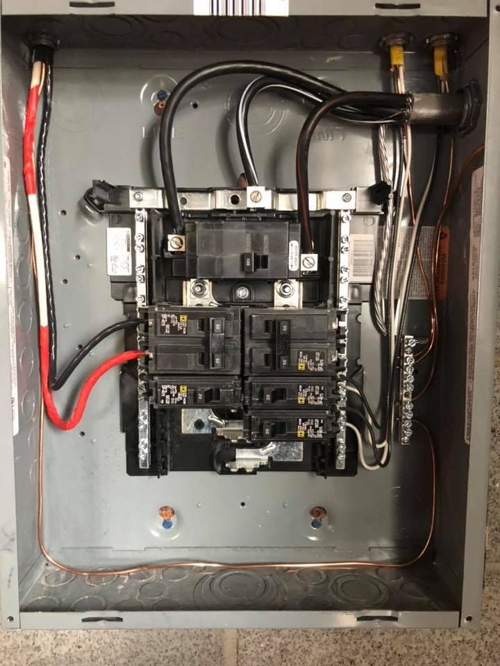 Electrical panel with black wires, silver bars, and copper grounding.