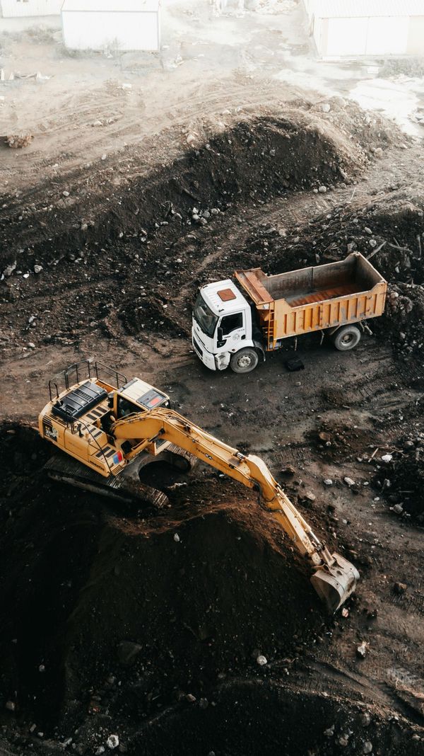 Excavator and dump truck working on a large dirt excavation site