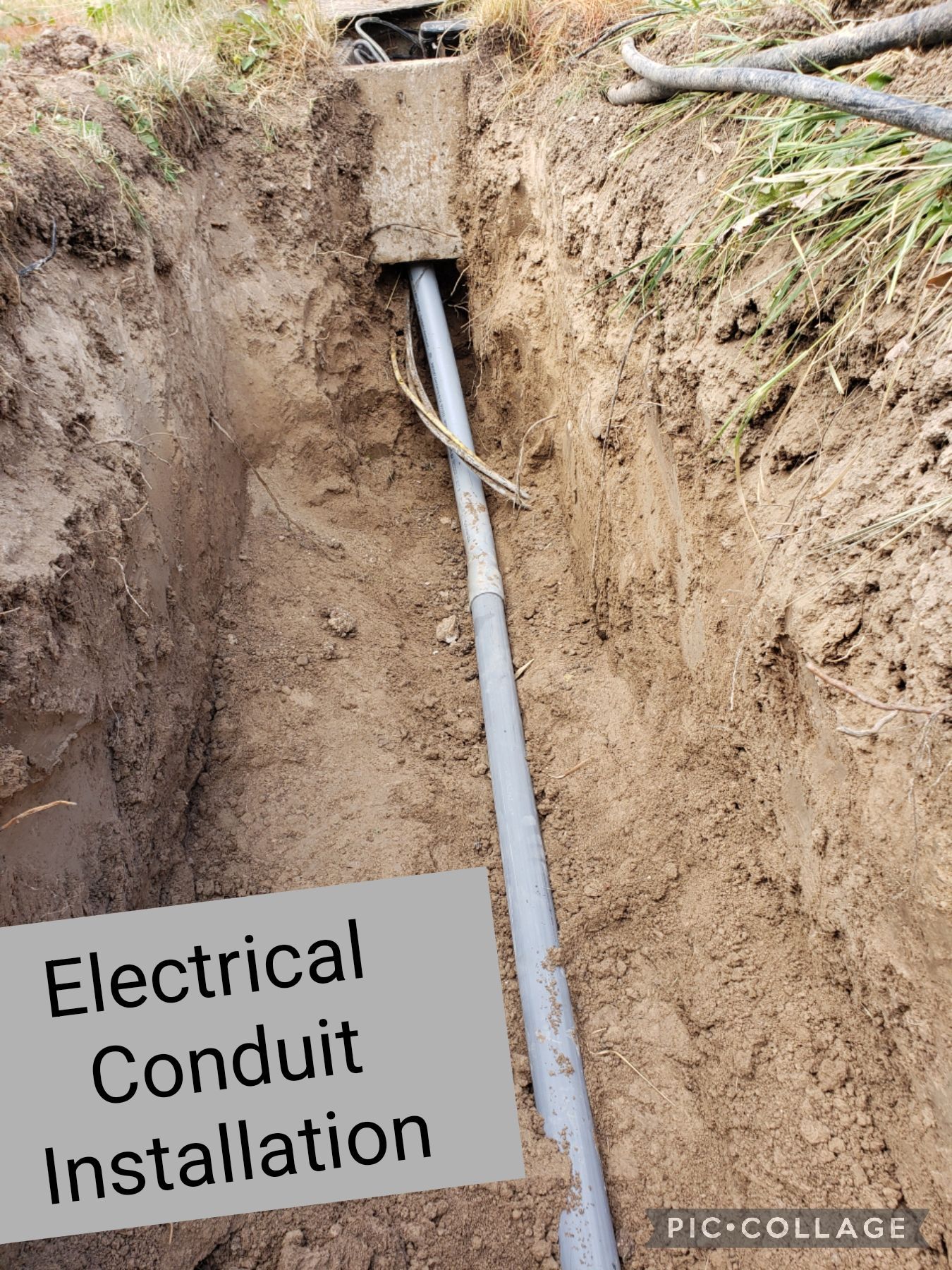 Electrical conduit installed in a dirt trench, leading from a concrete utility box.