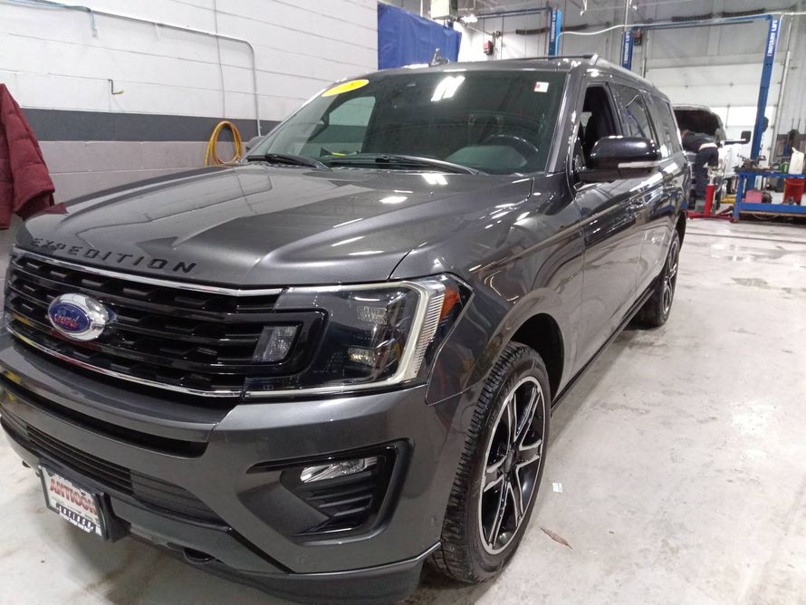 Gray Ford SUV in a service bay, front three-quarter view with headlights and grille visible