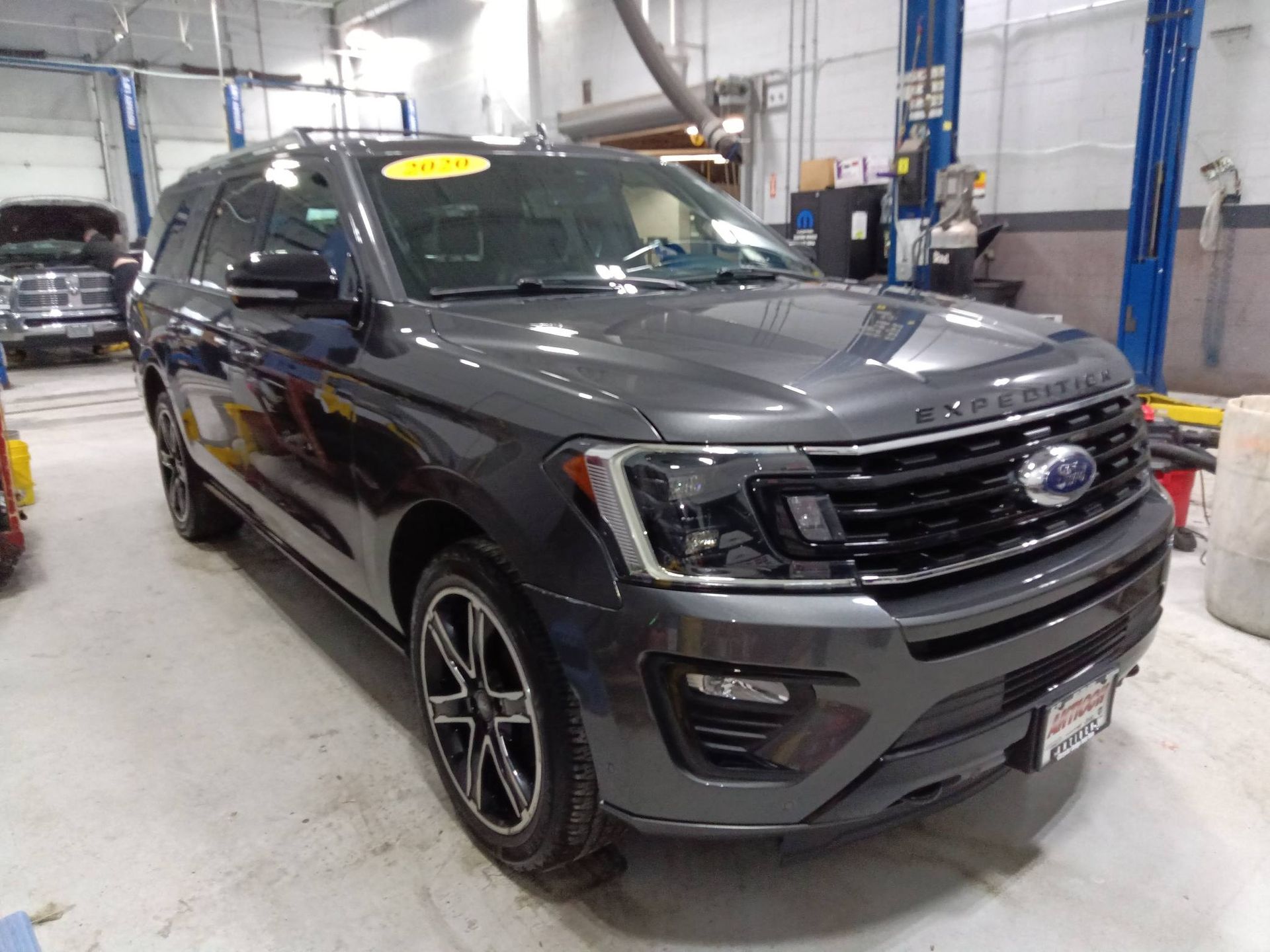 Black SUV parked inside an auto shop, viewed from the front-left side.