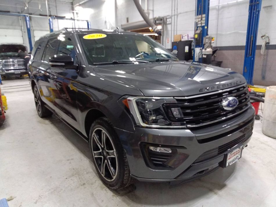 Black SUV parked in an auto shop bay with bright overhead lights and service equipment nearby