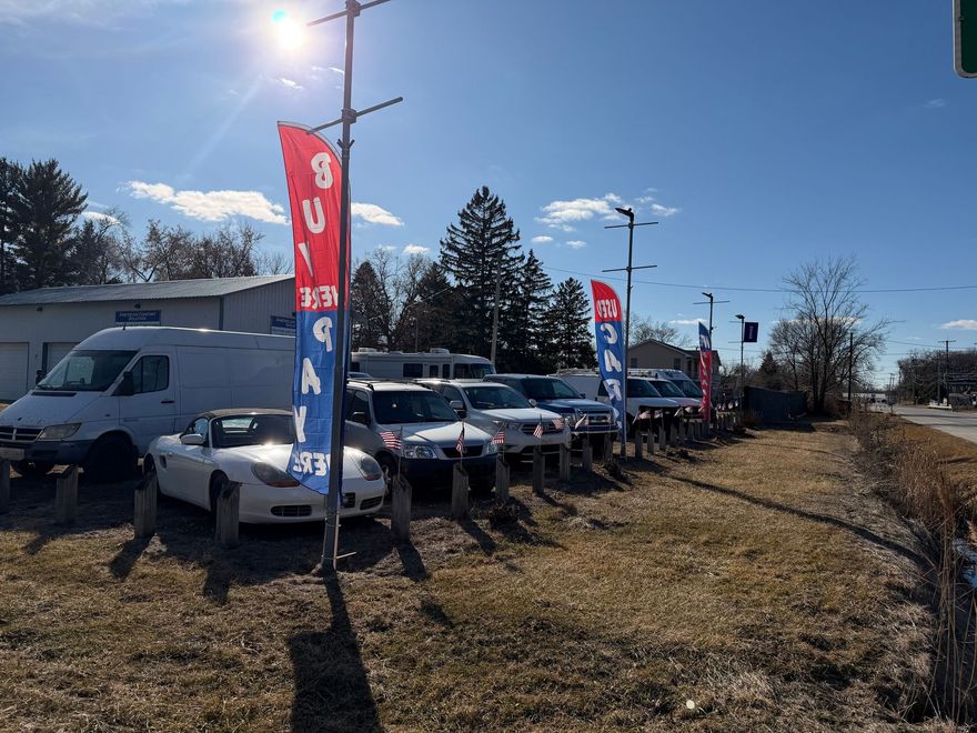 Row of parked trucks and SUVs with red, blue and white flags along a roadside under a sunny blue sky