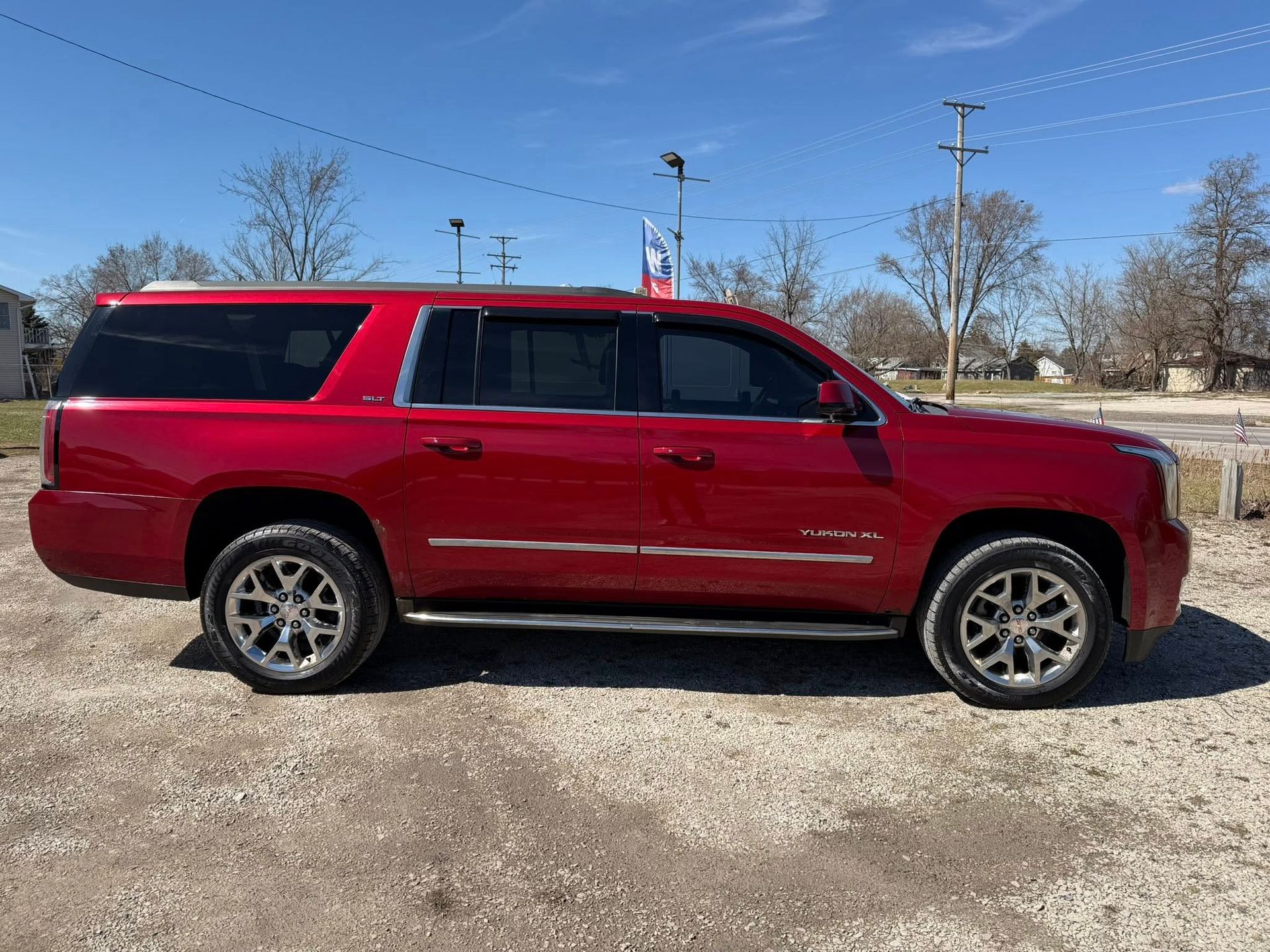 Red SUV parked on a gravel lot under a clear blue sky
