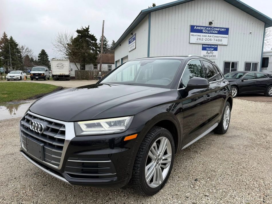 Black Audi SUV parked outside a car dealership on an overcast day