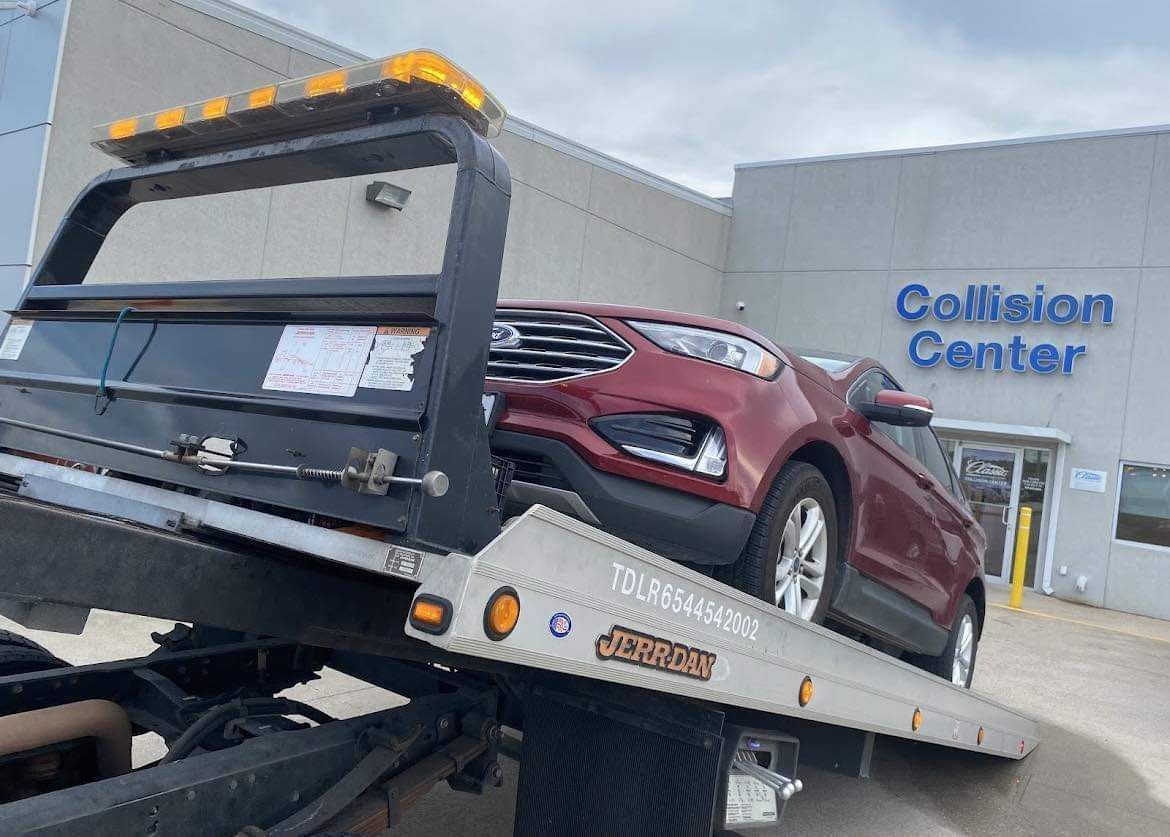 Maroon SUV on a tow truck outside a service center