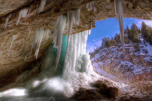Una cascada en una cueva con carámbanos colgando del techo.