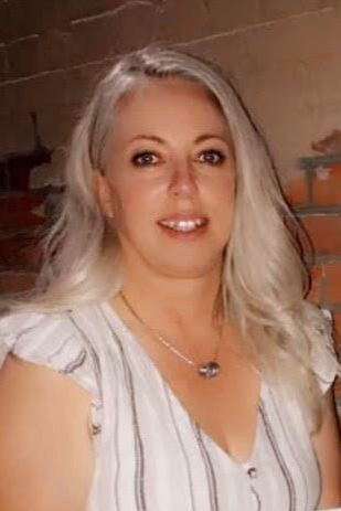 Una mujer está sentada frente a una pared de ladrillos.