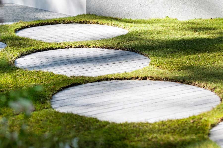 Circular stone stepping stones in a grassy yard, creating a path.