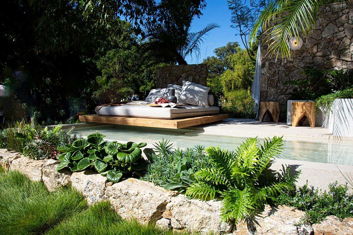 Outdoor pool area with a raised bed, surrounded by greenery and stone walls.