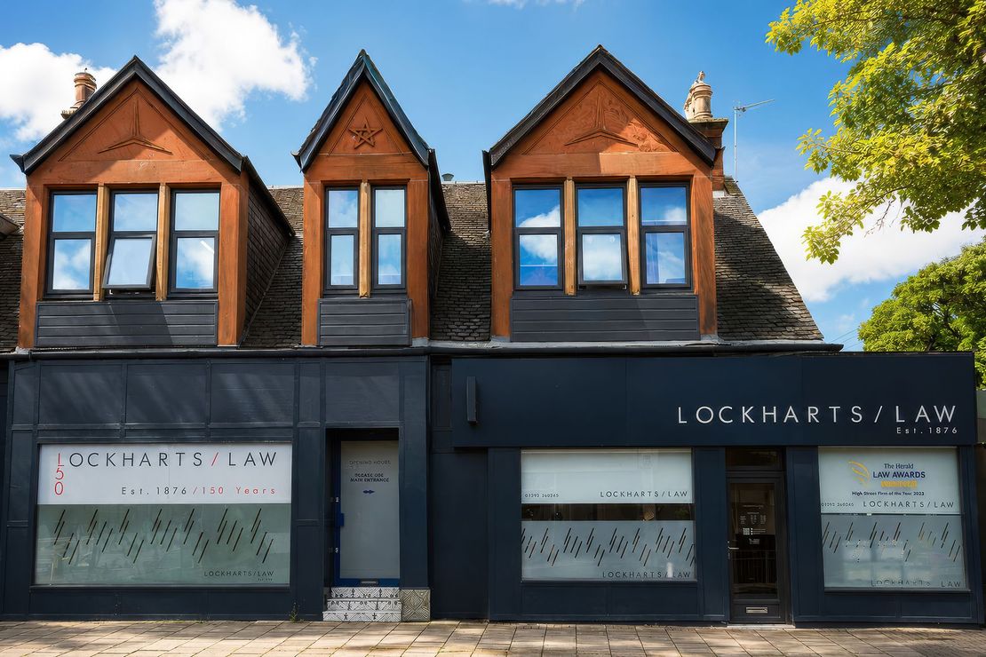 Two-story storefront with dark facade and wood dormers; sign reads “Lockhart’s Law”
