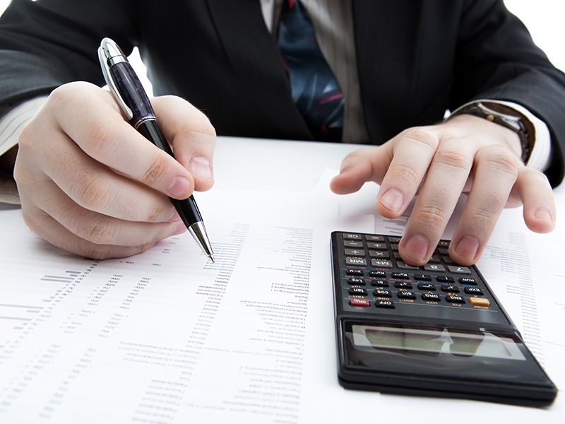 Person calculating finances on paperwork with a calculator and pen
