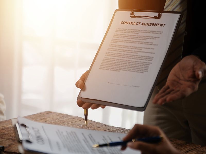 Pen signing a contract on a clipboard at a desk