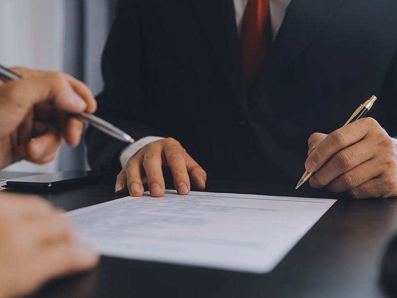 Hands signing a document at a business meeting table