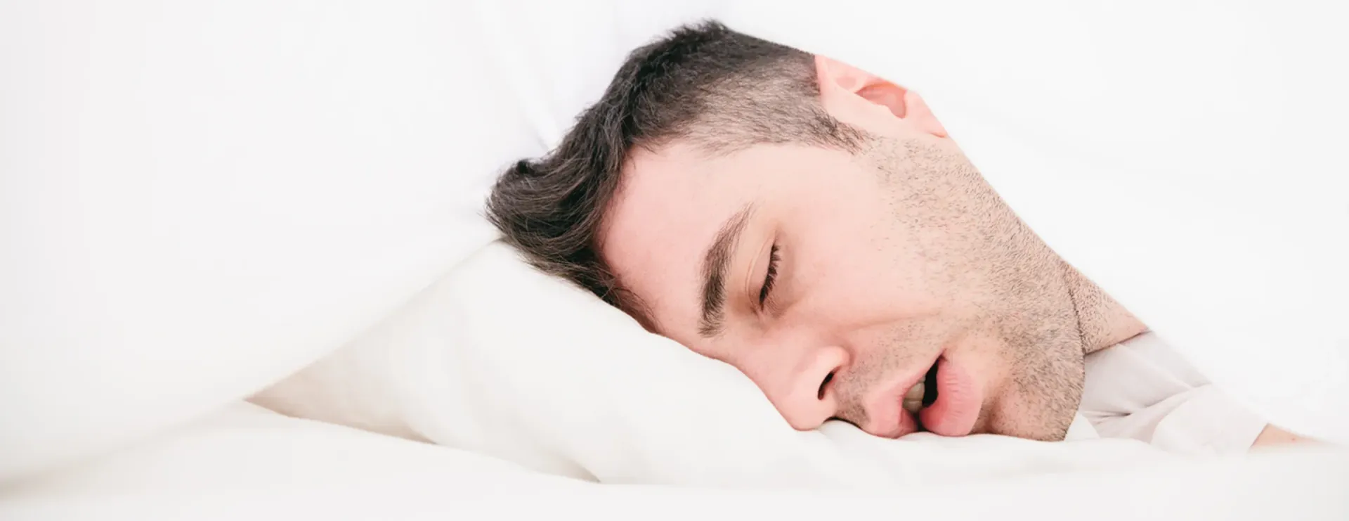 A man is sleeping on a bed with his head on a pillow.
