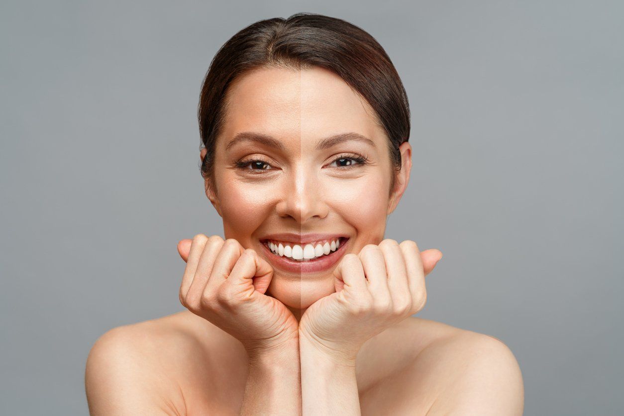 A woman is smiling with her hands on her face.