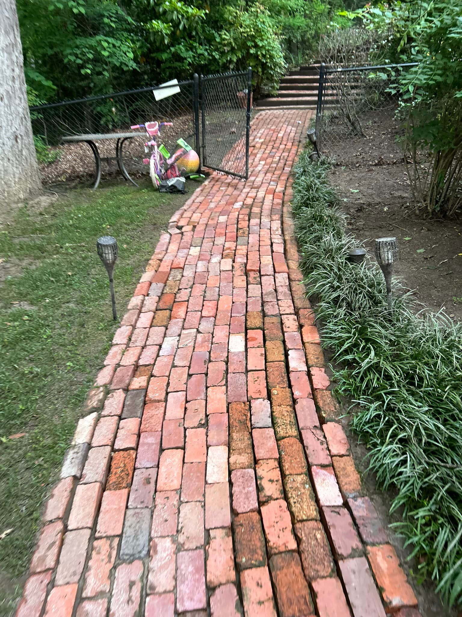 Curved brick garden path leading to steps, bordered by greenery and small solar lights