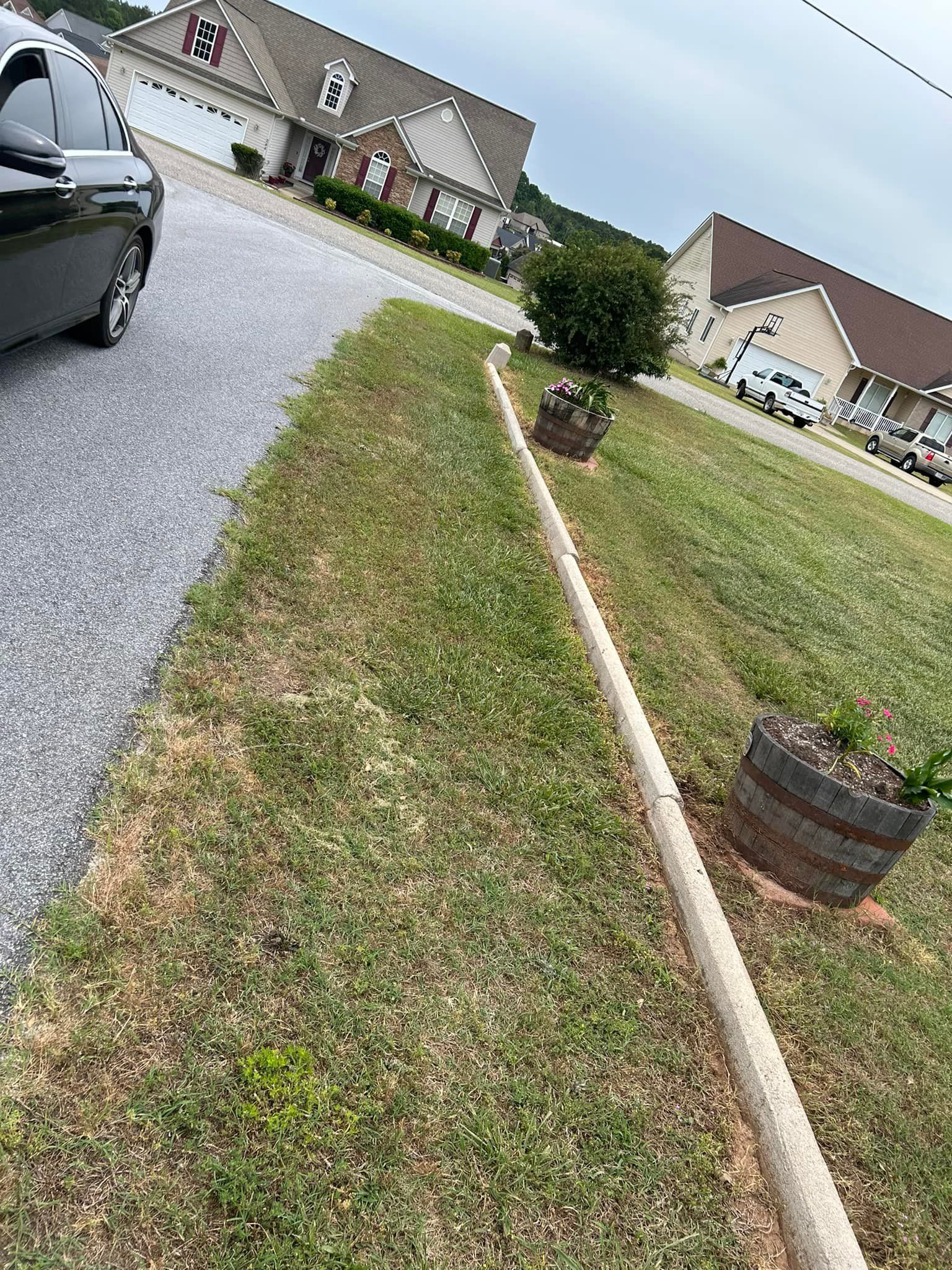 Tilting view of a suburban driveway, lawn, parked car, and a brick house under cloudy skies