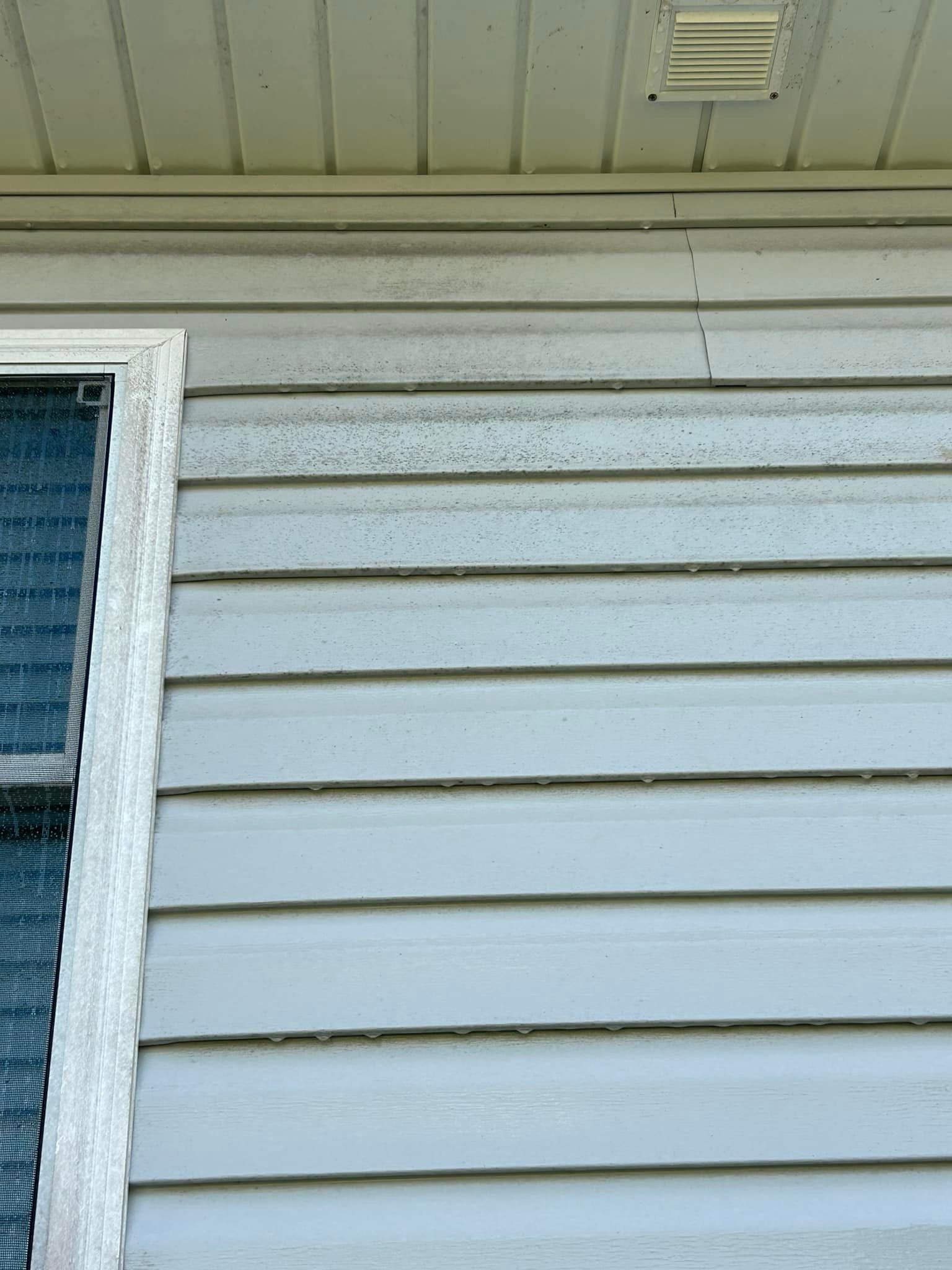 White house siding and a window under the eaves of a home exterior
