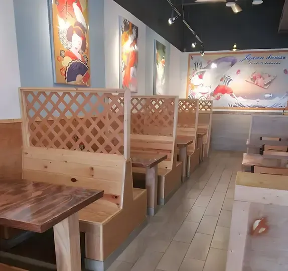 Empty restaurant with wooden booths and lattice dividers, tiled floor, and colorful wall art.