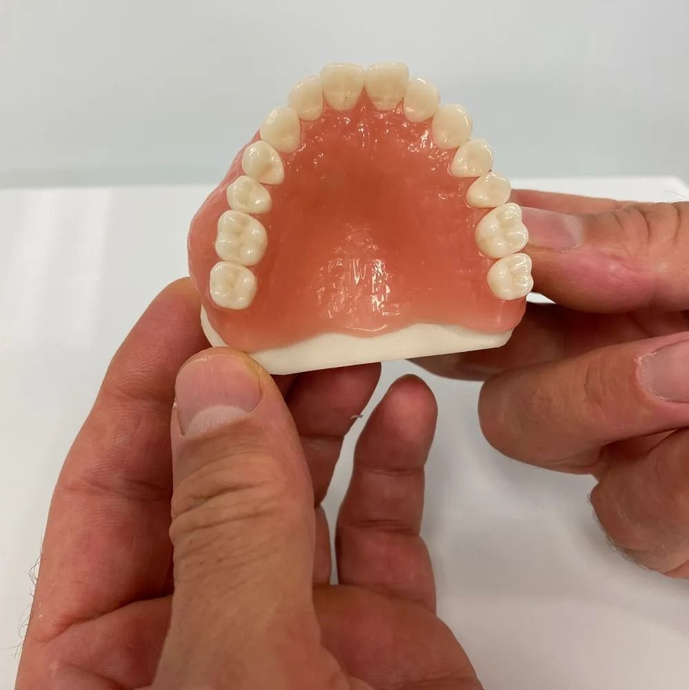 Hands Holding Pink Dentures on the Gold Coast