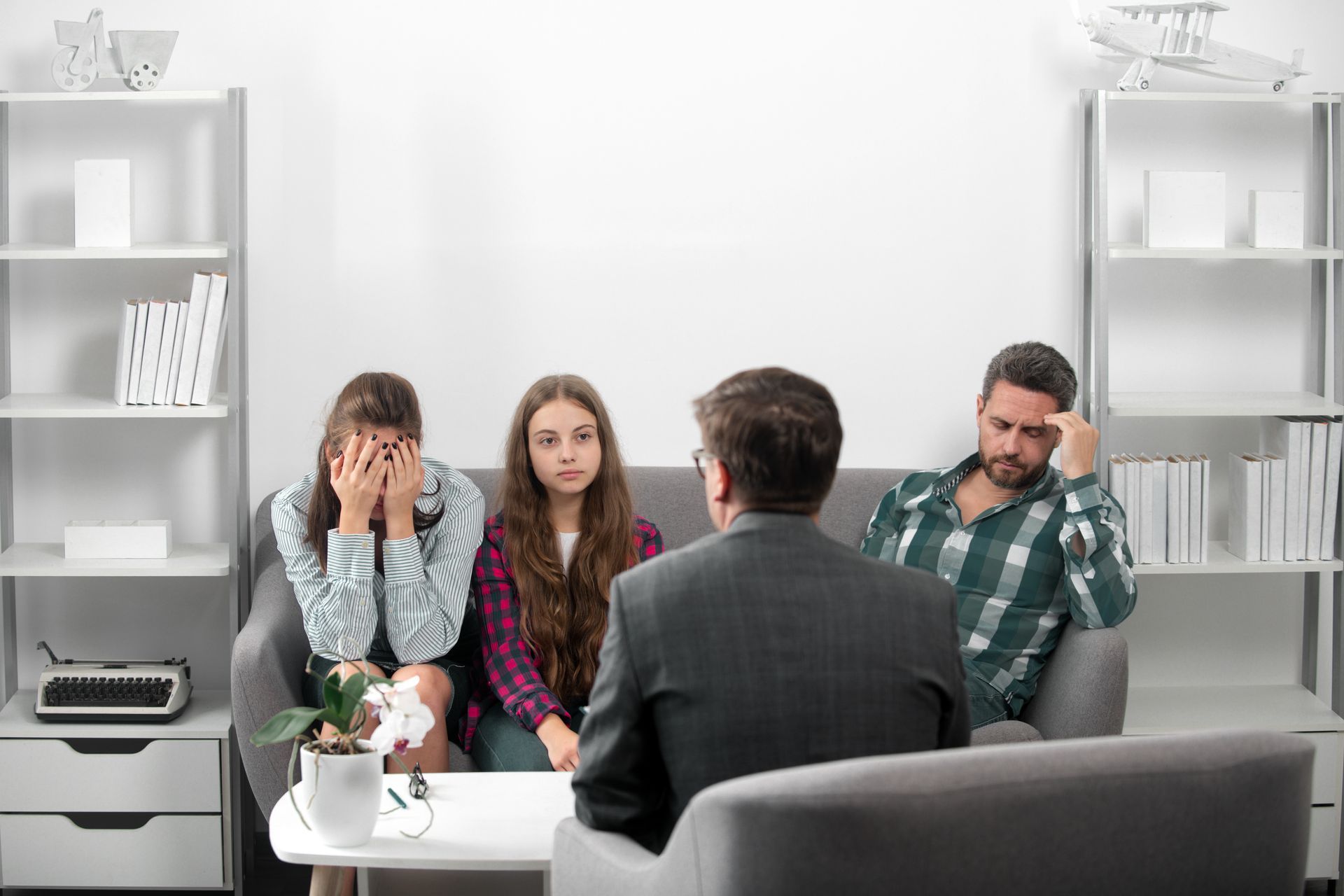 A family is sitting on a couch talking to a counselor.