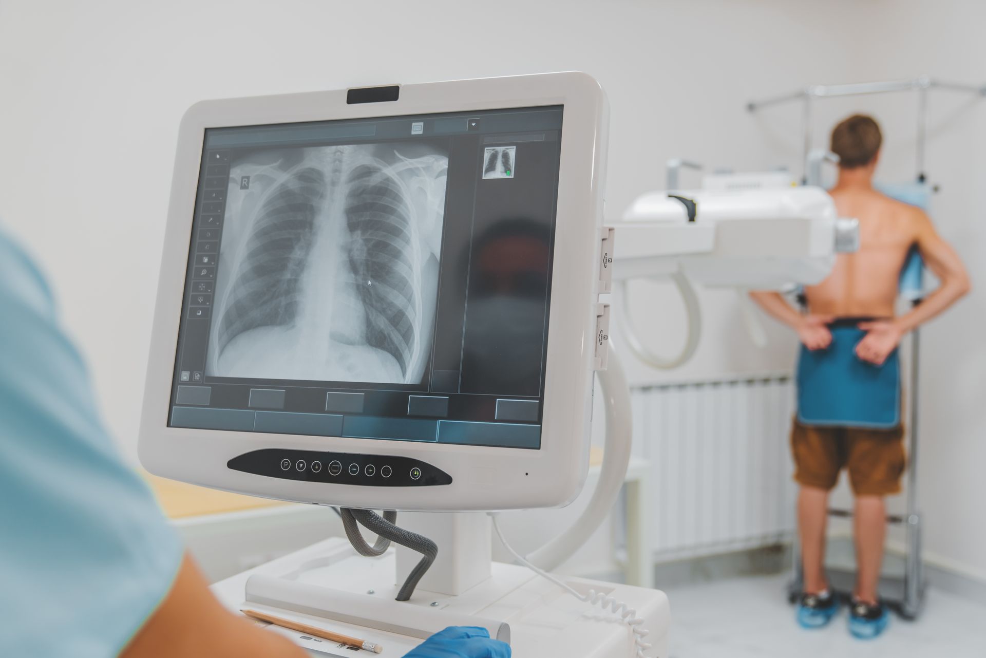 Man standing against wall while doctor using X-Ray machine scan him in hospital.