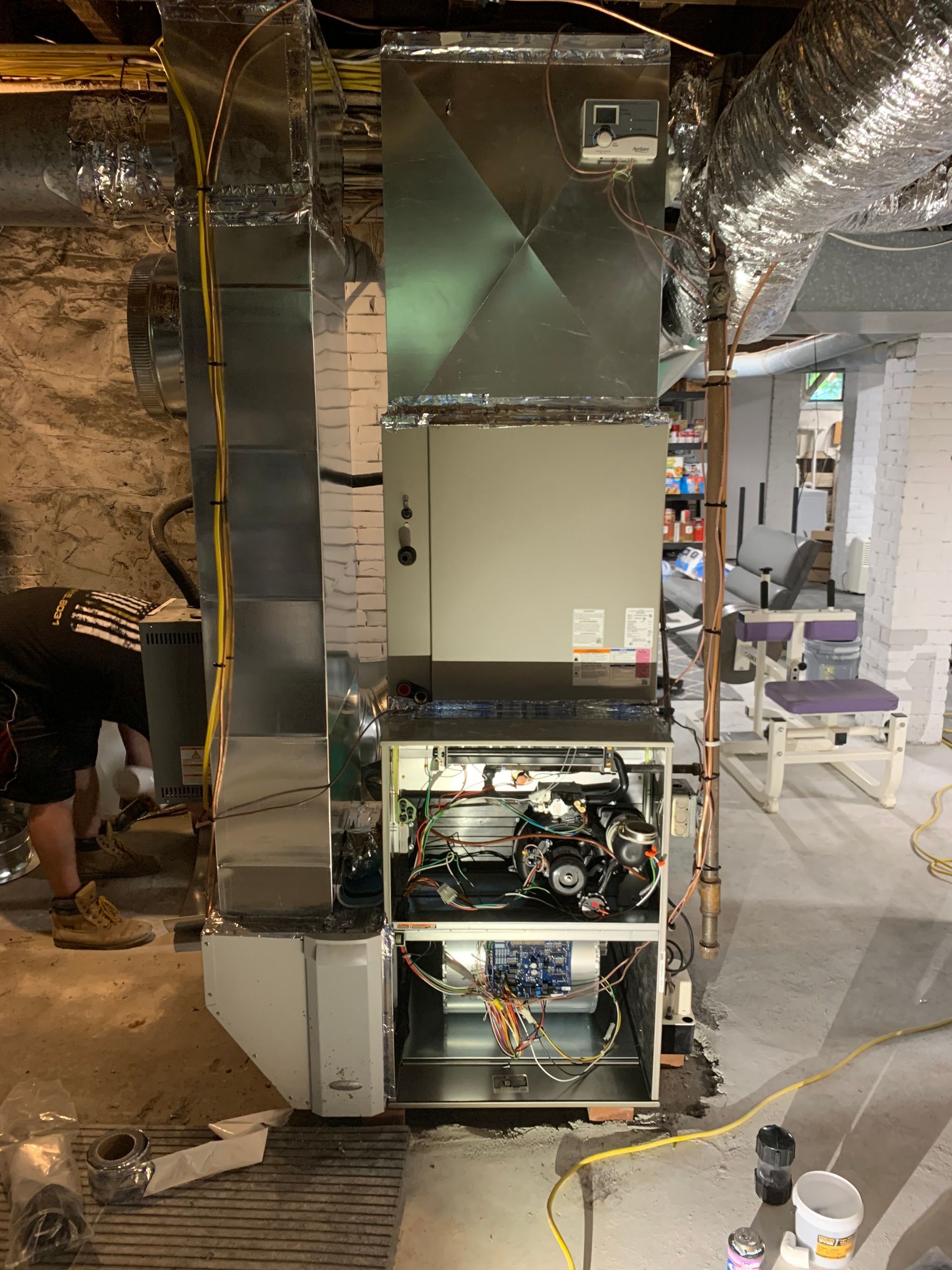 A man is working on an air conditioner in a basement.