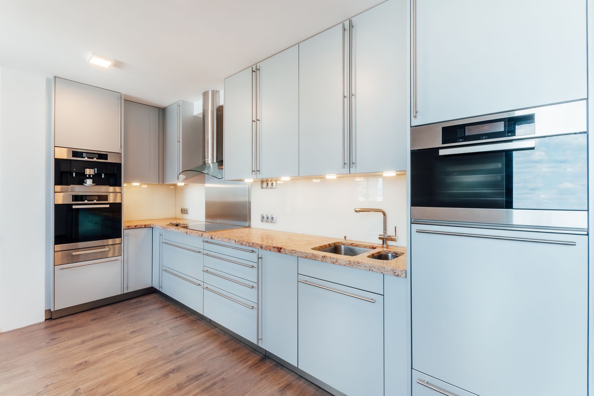Modern kitchen with light blue cabinets, stainless steel appliances, and granite countertops.