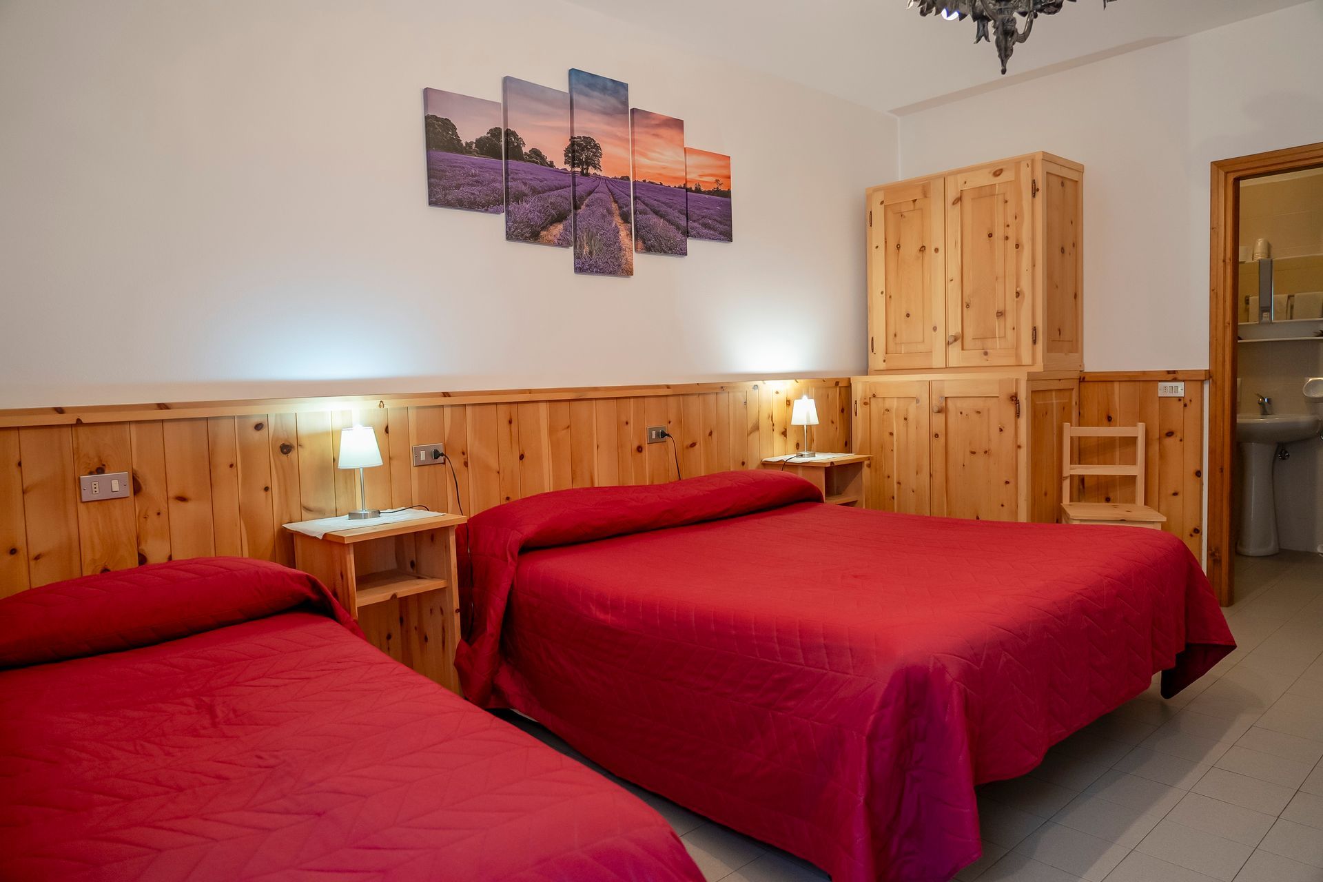 Una camera da letto con tre letti e un quadro sul muro.