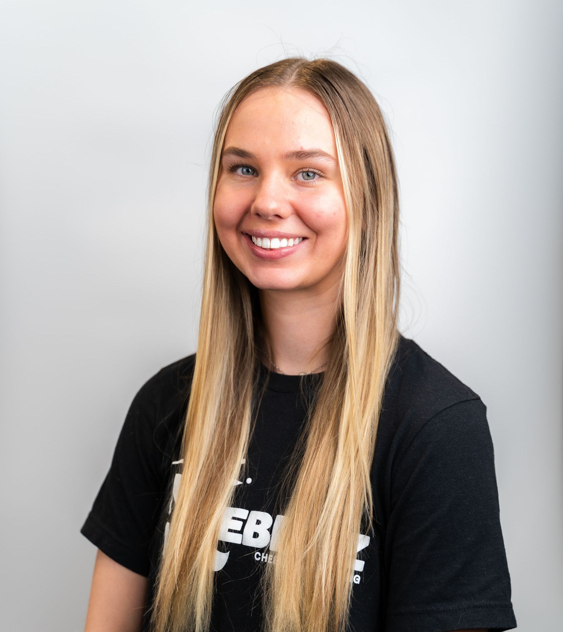 A woman in a black sweater is smiling with her arms crossed